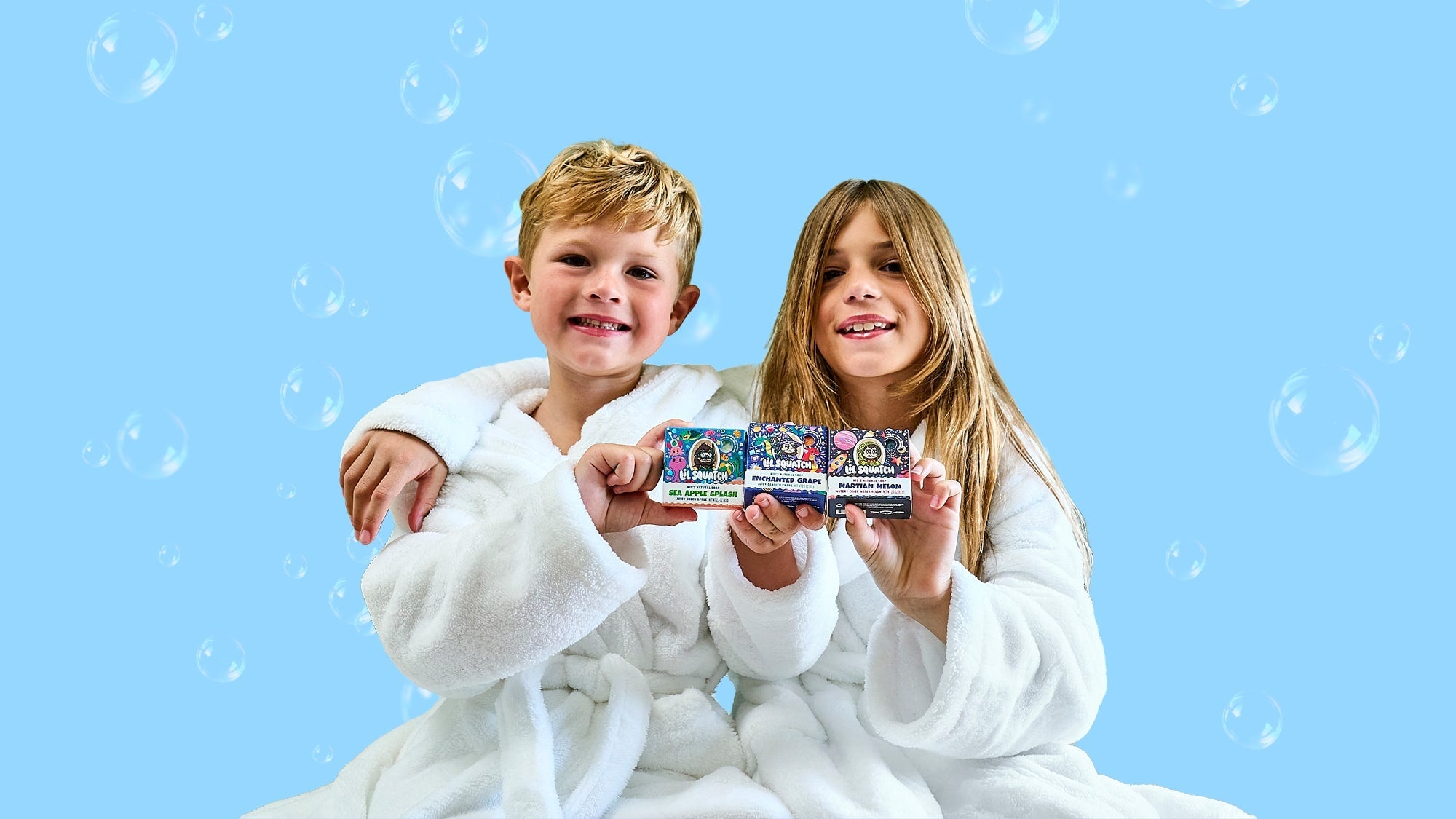 2 kids holding up 3 scents of lil squatch soaps